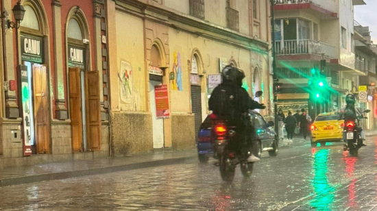 Una moto y vehículos circulan por la calle Tarqui, en Cuenca, durante las lluvias