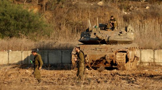 Soldados israelís caminan delante de un tanque en Metula, al norte de Israel, el 28 de noviembre de 2024, tras un acuerdo de alto el fuego con Hezbollah.