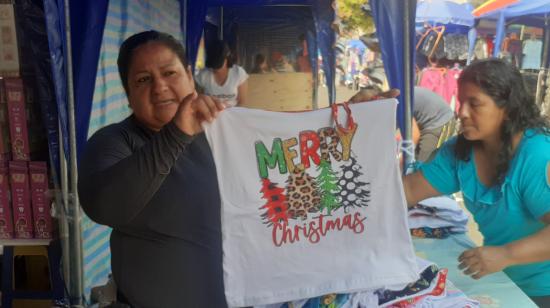 Blanca Costa, de 48 años, muestra una pijama navideña que vende en uno de los corredores navideños instalados para los comerciantes de Guayaquil. 12 de diciembre del 2024.