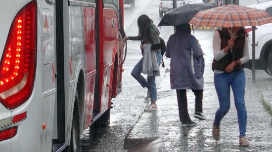 Mujer se sube a un bus en Cuenca en medio de una fuerte lluvia.