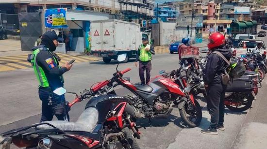 Agente de tránsito emite una multa durante un control a motos en Quito.