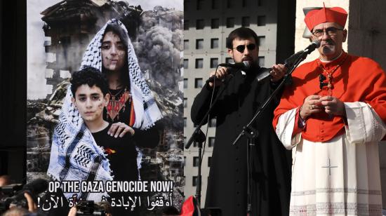 El patriarca latino de Jerusalén, Pierbattista Pizzaballa, da un discurso en Belén, en la Cisjordania ocupada por Israel, el 24 de diciembre de 2024. Junto a él, un poster con el texto "paren el genocidio en Gaza ahora" en inglés y árabe.