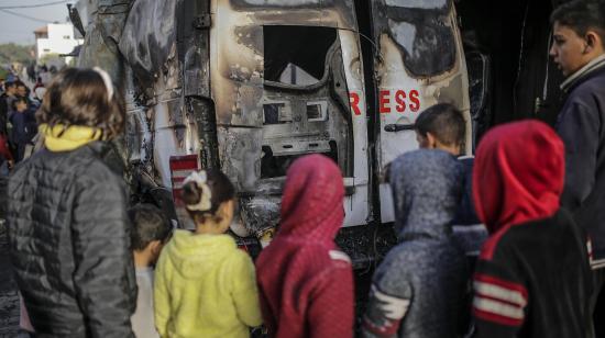 Palestinos observan un vehículo destruido con la palabra 'Press' (Prensa, en inglés) cerca del hospital Al Awda, después de un ataque aéreo en el campamento de refugiados de Al Nuseirat, en la Franja de Gaza, el 26 de diciembre de 2024.