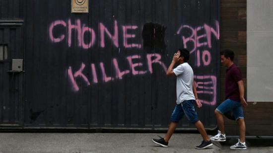 Dos jóvenes caminan junto a graffitis con el nombre de la banda criminal de los Chone Killers y su líder máximo, alias 'Ben 10', en el cantón Durán, provincia de Guayas, el 8 de octubre de 2023.