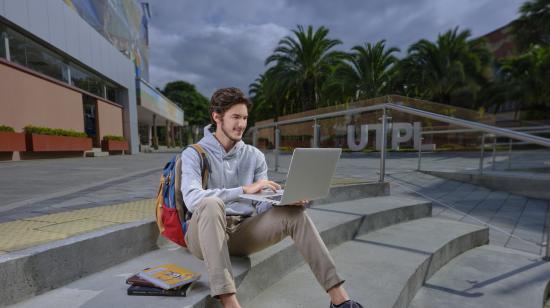 Estudiante de la UTPL con laptop en las instalaciones de la institución