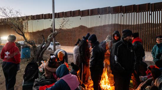 Migrantes junto a una fogata mientras esperan ser detenidos por oficiales de Aduanas y Patrulla Fronteriza de Estados Unidos después de cruzar una sección del muro fronterizo hacia los Estados Unidos el 5 de enero de 2025 en Ruby, Arizona.