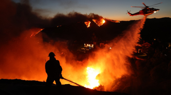 Un bombero y un helicóptero en el incendio Palisades