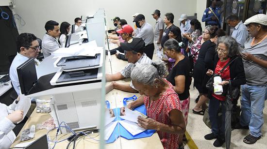 Fotografía referencial de ciudadanos que pagan tributos municipales en ventanillas físicas en Guayaquil.