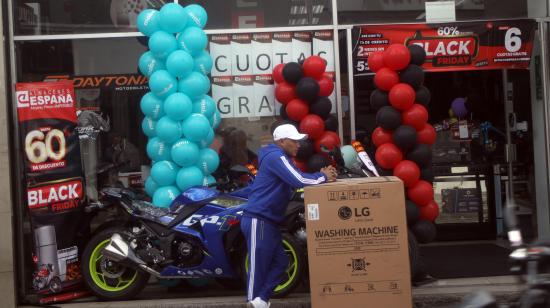 Una persona a las puertas de un comercio de venta de electrodomésticos y motos en Cuenca con descuentos por el Black Friday, en noviembre del 2024.