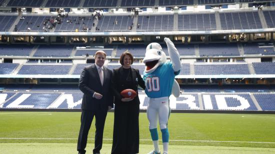 Brett Gosper, director de la NFL en Europa y Asia-Pacífico y Pri Shumate, vicepresidenta de los Miami Dolphins, en el césped del estadio Santiago Bernabéu con la mascota del equipo, durante el acto celebrado este viernes 17 de enero en Madrid en el que la NFL, la Liga profesional de fútbol americano, ha anunciado que los Miami Dolphins serán el 'equipo designado' (local) en el partido de ese campeonato que se disputará este año en el mencionado estadio de la capital.