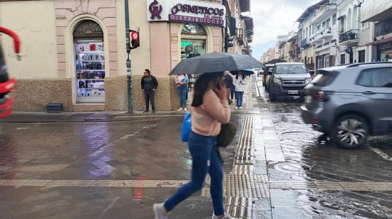 Una mujer se protege con un paraguas de la lluvia en el centro de Cuenca (Azuay), el 30 de abril de 2025.