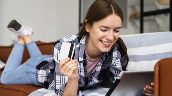 Mujer mirando su tableta y sosteniendo una tarjeta de crédito.