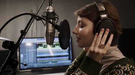 Imagen referencial de una mujer grabando su voz en un estudio profesional.