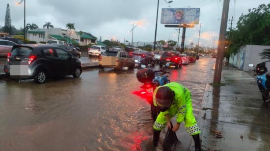 Un agente de la ATM despeja una alcantarilla tapada en una avenida inundada, norte de Guayaquil, el 19 de octubre de 2026.