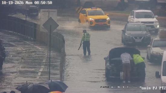 Un agente de la ATM en una de las avenidas inundadas en el norte de la ciudad, y varios carros varados, Guayaquil, el 19 de octubre de 2026.