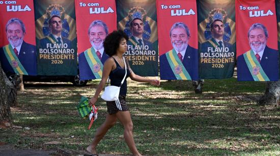 Una mujer camina frente a un puesto de venta ambulante con banderas de los candidatos presidenciales Lula Da Silva y Flavio Bolsonaro, en Brasilia, el 22 de octubre de 2026.