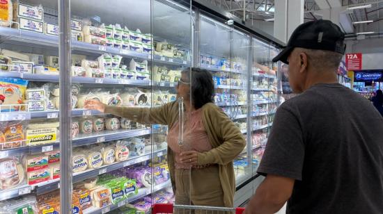 Consumidores en la sección lácteos de un supermercado.