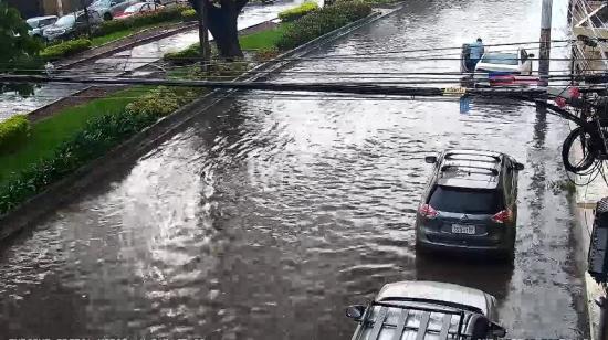 Un conductor empuja su vehículo en una calle inundada en la intersección de Enrique Ortega y Pasaje 32, en Guayaquil, este viernes 23 de octubre de 2026.