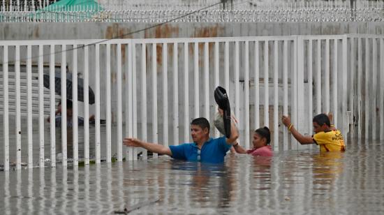 Personas caminan por aguas anegadas tras fuertes lluvias en el norte de Guayaquil, Ecuador, el 26 de octubre de 2026.