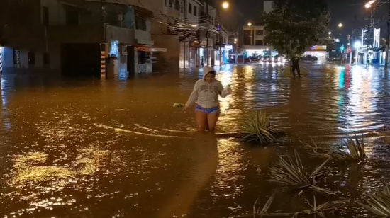 Una mujer camina en una calle cubierta por el agua en Guayaquil, el 26 de octubre de 2026.