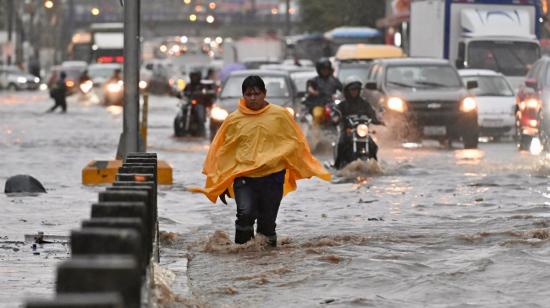 Un hombre camina por aguas anegada tras fuertes lluvias en el norte de Guayaquil, el 26 de octubre de 2026, tras la tormenta que colapsó la ciudad.