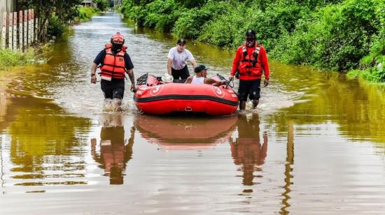 Bomberos de Machala evacúan a un adulto mayor por las inundaciones en la zona norte de la ciudad, el 27 de octubre de 2026.