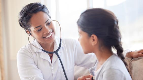 Médico examinando a una niña con un estetoscopio.