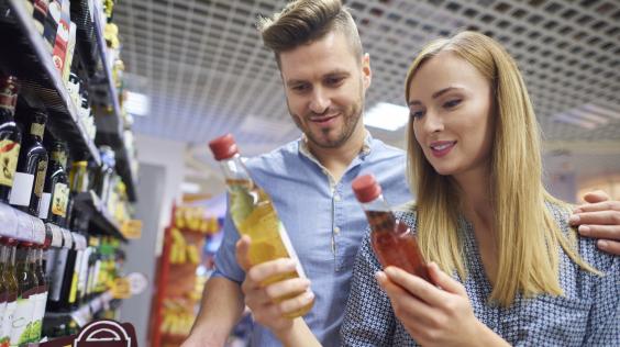 Hombre y mujer comparando precios de productos en supermercado