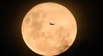 La silueta de un avión se perfila sobre la superficie de la luna llena, en Sídney, Australia.