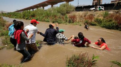 Migrantes hondureños y salvadoreños hacen una cadena para cruzar el Río Bravo en la frontera entre México y Estados Unidos.