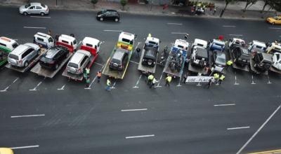 Agentes de la Agencia Nacional de Tránsito junto a las grúas y algunos de los vehículos retenidos por circular sin placas.