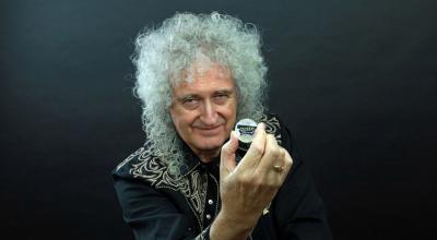 El guitarrista de Queen, brian May, sostiene una de las monedas conmemorativas con el logotipo de la banda.