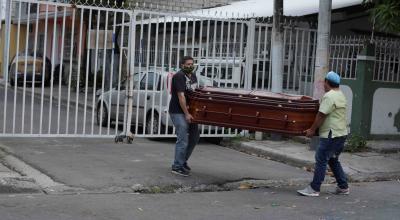 Un familiar y el trabajador de una funeraria cargan el ataúd de una mujer que falleció en casa por posible coronavirus el 31 de marzo de 2020 en Guayaquil.