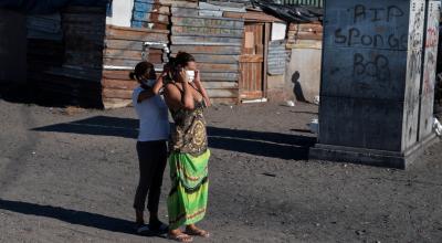 Una señora le coloca una mascarilla a otra, el 28 de abril de 2020, en Cape Town, Sudáfrica.