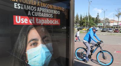 Un hombre circula en bicicleta junto a un anuncio que fomenta el uso de mascarillas, en Bogotá, Colombia, el 25 de agosto de 2020.
