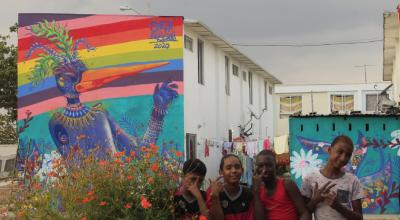 Niños del barrio Nuevo Ceibos saludan a la cámara, mientras que la obra de Carla Bresciani descansa detrás de ellos.