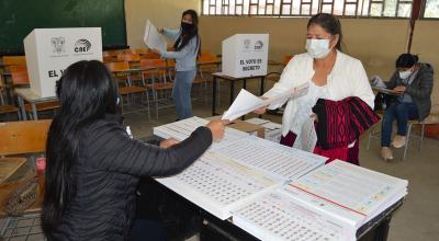 Una ciudadana recibe las papeletas electorales en un recinto de Cuenca, durante las elecciones presidenciales y legislativas del 7 de febrero de 2021.