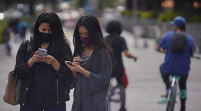 Dos mujeres miran sus celulares el 18 de septiembre de 2020 en la avenida Naciones Unidas, en el norte de Quito.
