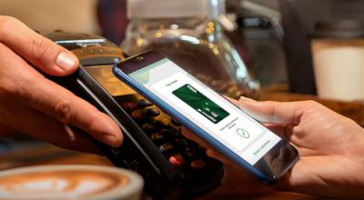 Una persona utiliza su teléfono inteligente para hacer un pago en una cafetería. 