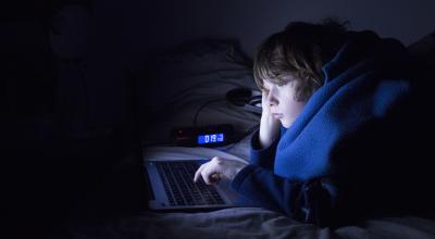 Menor de edad frente a una computadora durante la madrugada.