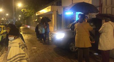 Ciudadanos esperan bajo la lluvia su entrada el colegio Sebastián de Benalcázar, en Quito, la noche del 26 de abril de 2021.