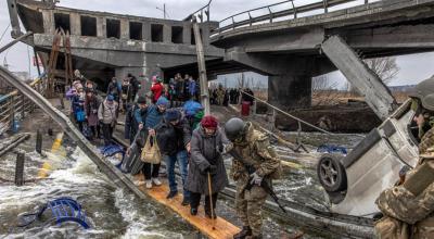 Civiles cruzan un puente destruido mientras huyen del asedio en la ciudad de Irpin, a unos 20 km de la capital, en Ucrania, el 7 de marzo de 2022.