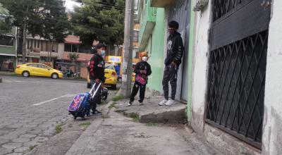 Tres personas conversan sobre una vereda en mal estado en el sur de Quito, el 13 de abril de 2022.