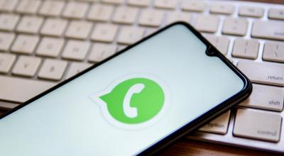 Un teléfono inteligente con el logo de WhatsApp, sobre un teclado. 