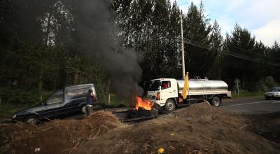 Vehículos se abren paso a un costado de la vía que ha sido bloqueada por manifestantes, en Cotopaxi, el 14 de junio de 2022.