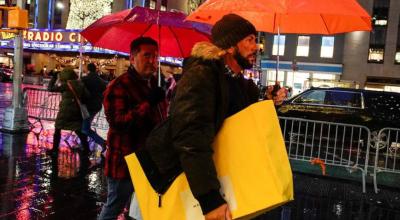 Un hombre camina bajo la lluvia con su bolsa de compras durante la temporada navideña en la ciudad de Nueva York, EE. UU., el 15 de diciembre de 2022