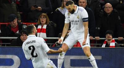 Karim Benzema del Real Madrid celebra con su compañero Dani Carvajal tras marcarle al Liverpool en la Champions League, el 21 de febrero de 2023.