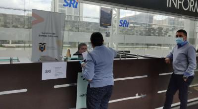 Personas hacen fila en la ventanilla de atención del Servicio de Rentas Internas (SRI) en la Plataforma Financiera, en el norte de Quito.