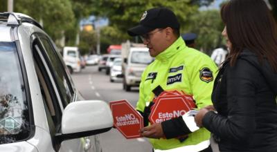 Un agente de tránsito  de Cuenca da información a un conductor sobre una campaña de educación vial.