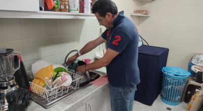 Un hombre intenta lavar sus platos en su casa, ubicada en Turubamba.